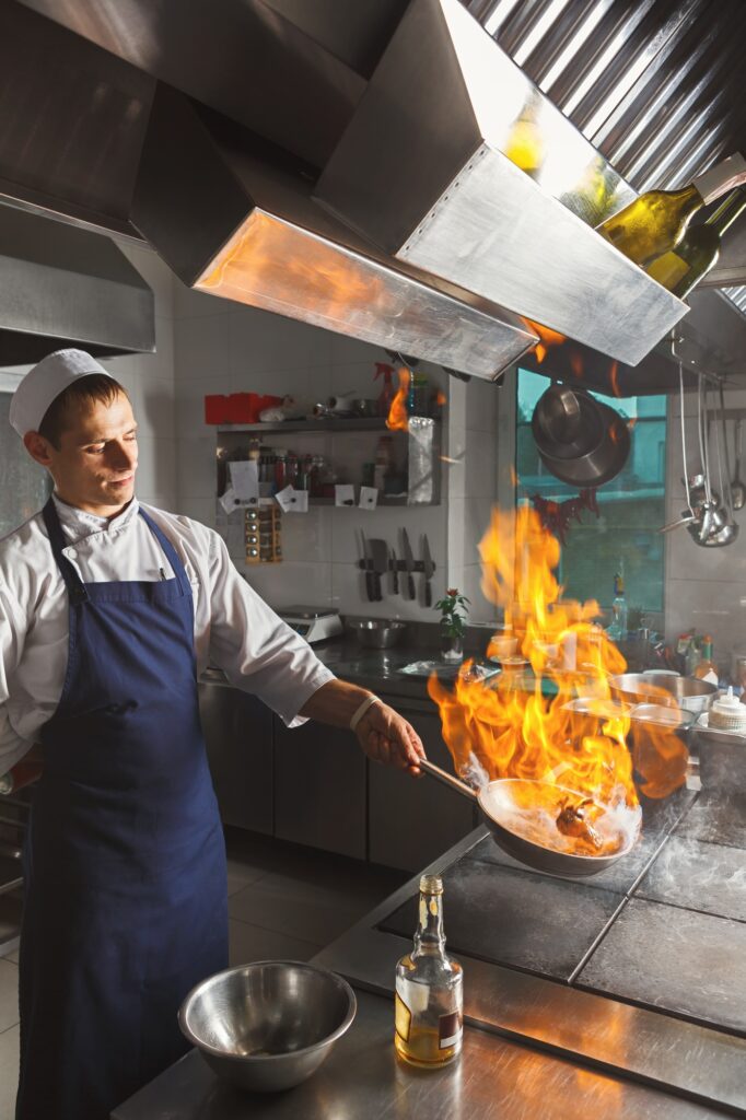 Chef cooking juicy beef steak at restaurant kitchen